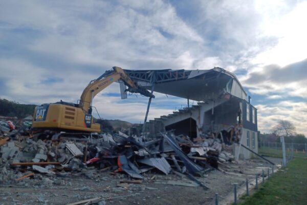 image of Scope Group excavator demolishing rugby grandstand in North Otago, New Zealand
